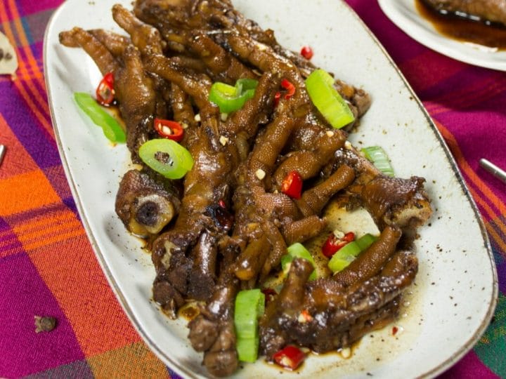filipino chicken feet in soy sauce adobo on plate with garnish